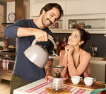 Homem servindo uma xícara de café Café Apricot na xícara de café de sua esposa na mesa da cozinha