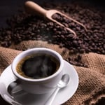 Uma xícara de café com grãos de café e uma concha de madeira